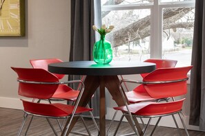 Une table ronde avec un vase vert et des chaises rouges, dans une pièce dotée d’une fenêtre.