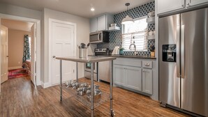 Una cocina moderna con electrodomésticos de acero inoxidable, una estantería de alambre y un salpicadero con diseño.