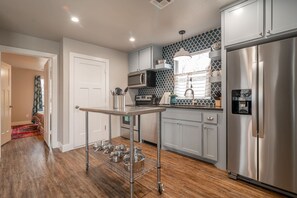 Una cocina moderna con electrodomésticos de acero inoxidable, una estantería de alambre y un salpicadero con diseño.