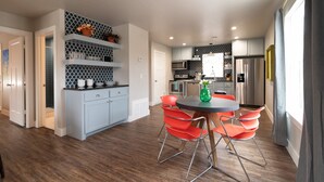 Una cocina moderna con armarios grises, encimera negra y zona de comedor con sillas rojas.