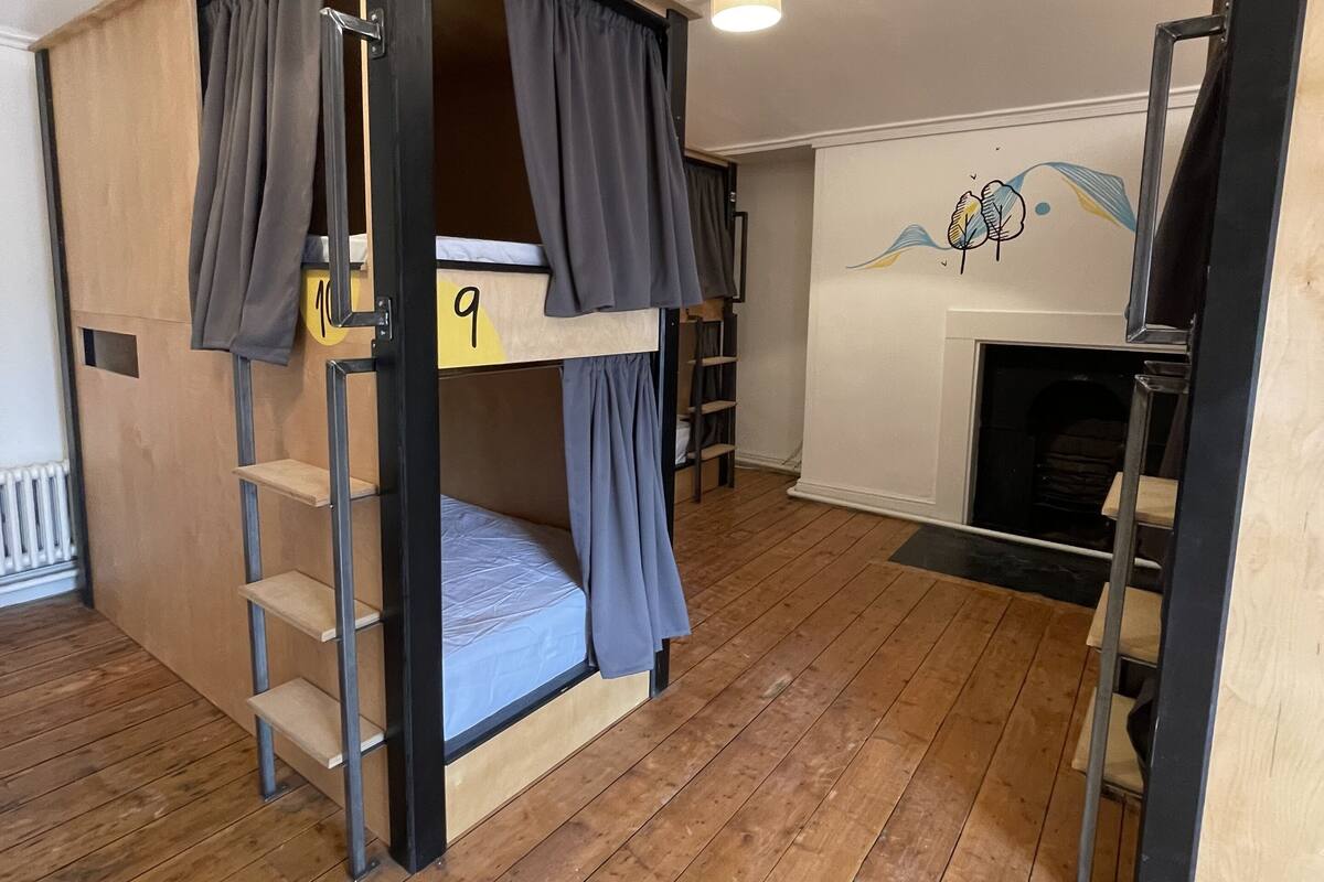 Habitación con literas, piso de madera, ventilador de techo y chimenea.