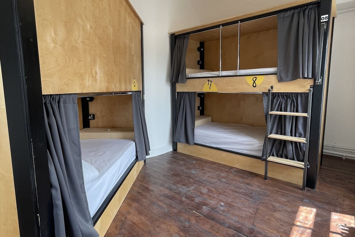 Un dormitorio con literas, suelo de madera y una lámpara en el techo.
