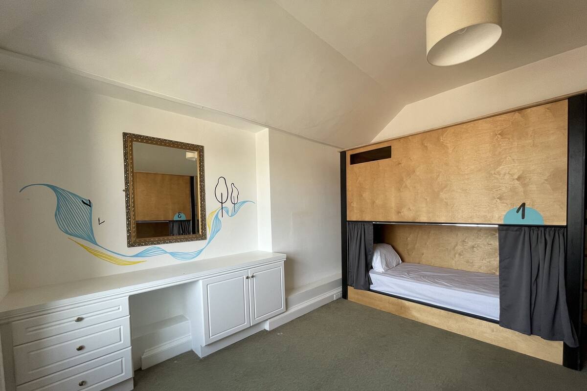 Un dormitorio con una cama litera, un aparador, un espejo y un adhesivo en la pared.