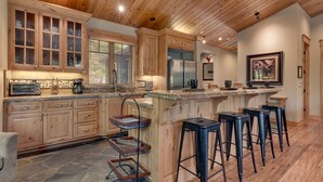 Una cocina amplia con armarios de madera, encimera de granito y una barra con taburetes.