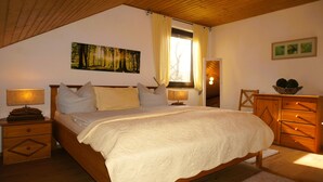 Un dormitorio con una cama grande, dos mesitas de noche con lámparas, un aparador de madera y un cuadro en la pared.