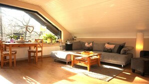 Una sala acogedora con una mesa de comedor de madera, un sofá gris y una mesa baja.