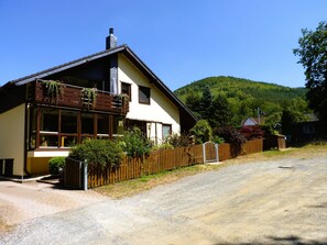 Ein zweistöckiges Haus mit Balkon, einem Schotterweg und einem Holzzaun.