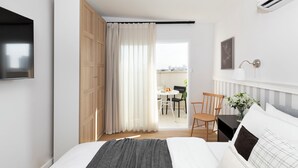 A modern hotel room with a bed, a TV, a desk, and a view of the city through the window. - AirTLV - Arlozorov Apartment's (Ramat Gan)