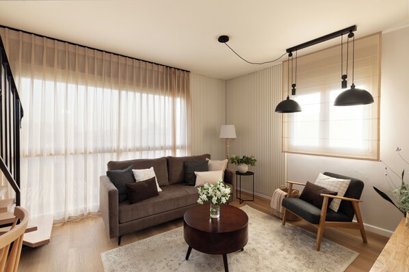 A modern living room with a sofa, armchairs, a coffee table, and a lamp.
