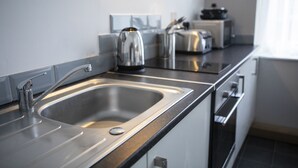 A modern kitchen with a stainless steel sink, a kettle, and a toaster. - Wellington Apartments (Norwich)