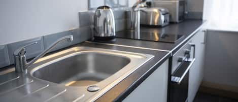 A modern kitchen with a stainless steel sink, a kettle, and a toaster.