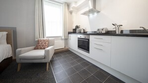 A modern kitchen with white cabinets, a black countertop, and a built-in oven. - Wellington Apartments (Norwich)
