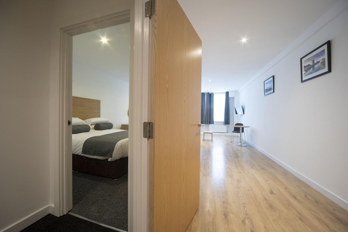 A hotel room with a bed, a desk, and a chair.
