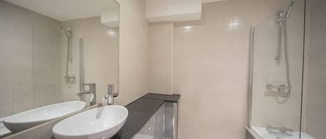 Un baño moderno con lavamanos doble, inodoro y ducha con mampara de vidrio.