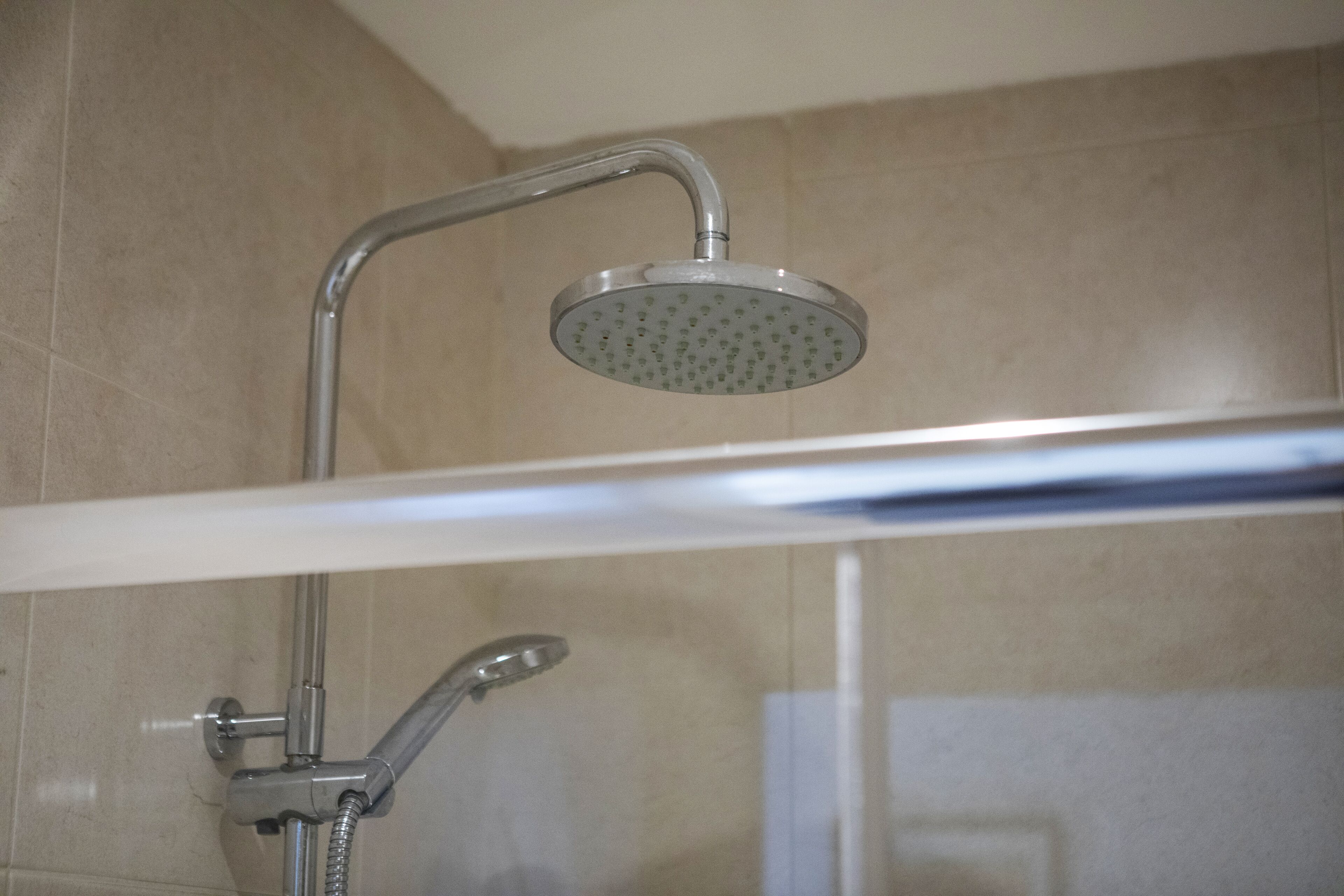 A shower with a handheld showerhead and a fixed overhead showerhead.