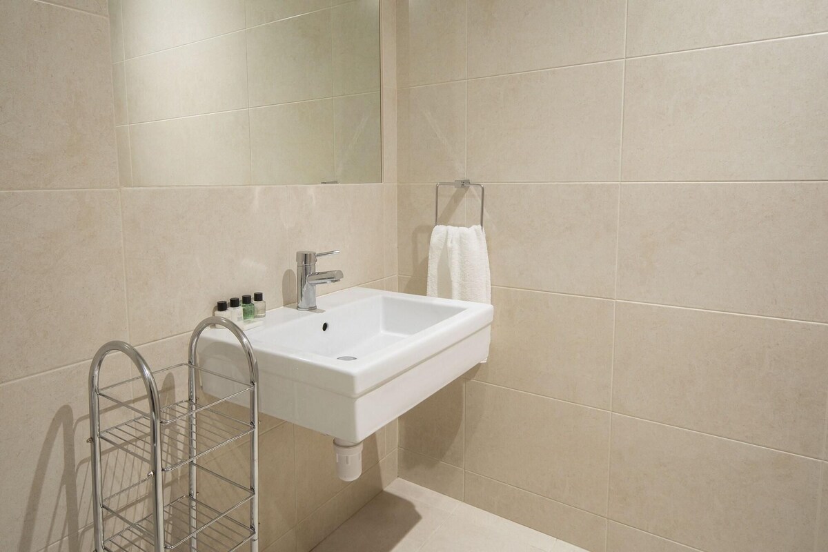 A bathroom with a white sink, a towel rack, and a metal rack.