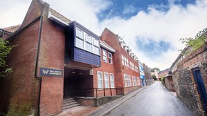 A street view of Wellington Apartments, featuring a mix of brick and modern facade buildings, a narrow road, and a clear sky. - Wellington Apartments (Norwich)