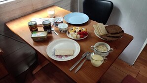 Een houten eettafel met diverse ontbijtartikelen zoals yoghurt, brood en fruit.