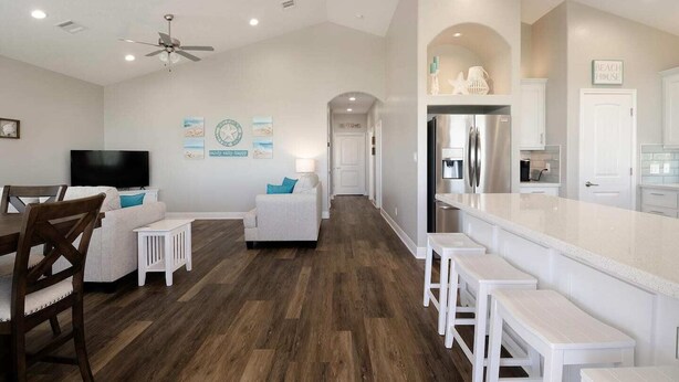 A spacious living area with a dining table, sofa, and a kitchen with a large island and bar seating. - Crystal Sands - 3 bedroom, 2 bath home that sleeps 8 - Easy Beach Access! (Crystal Beach)