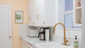 A kitchen with white cabinets, a marble countertop, and a gold faucet. - Charming cozy cottage on historic numbered streets (Idaho Falls)