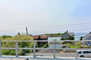 A coastal view with a white bridge, a parking area, and houses with a view of the sea.