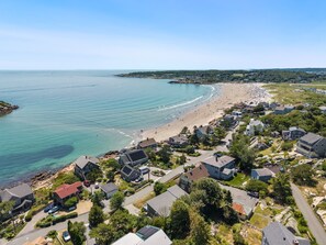 A coastal residential area with houses, a beach, and a clear view of the ocean.