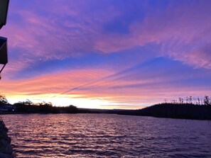Un coucher de soleil sur une étendue d’eau, avec un ciel dégagé.