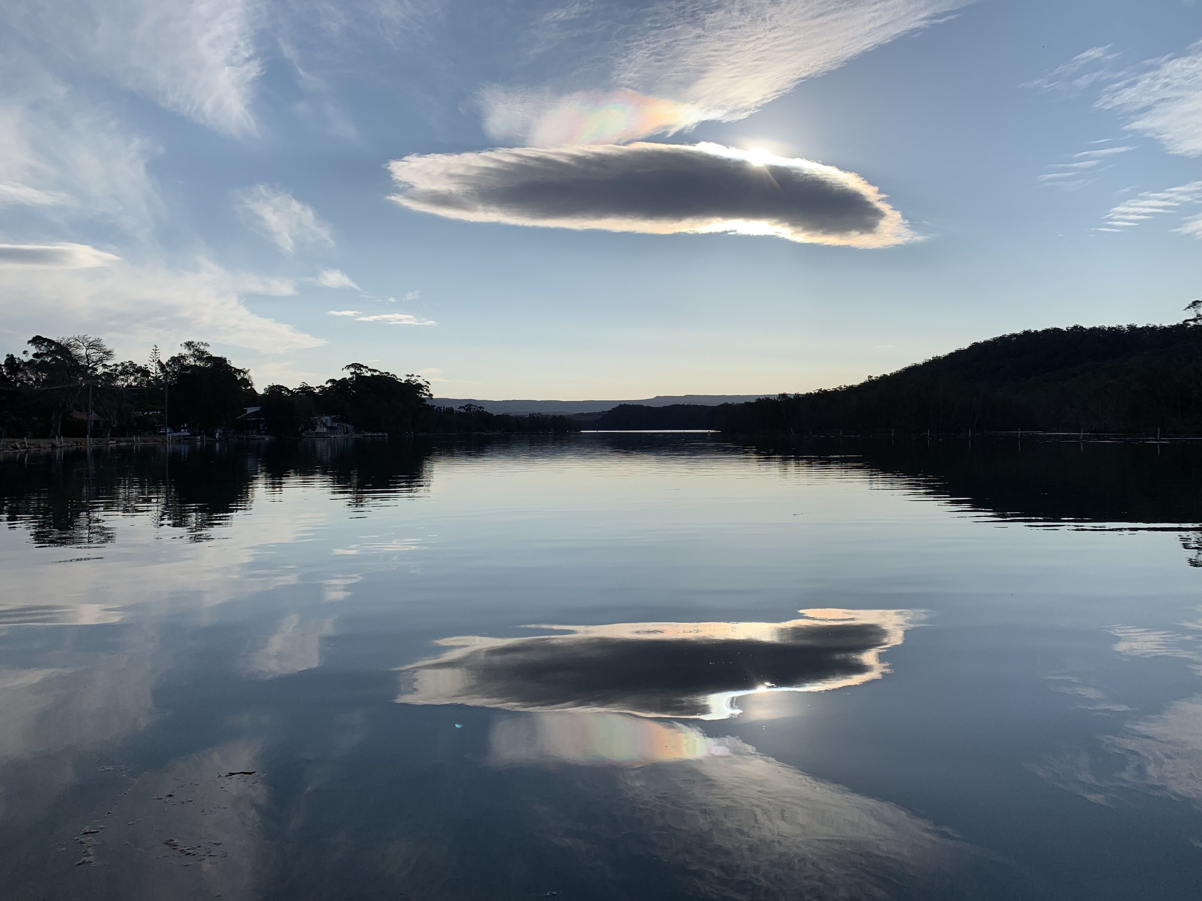 A calm lake with a clear sky and a rainbow.