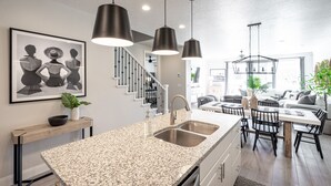 A modern kitchen with granite countertops, stainless steel sinks, and pendant lighting.