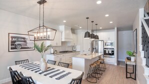 A modern kitchen with white cabinets, a central island, and pendant lighting.