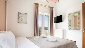 Een hotelkamer met een bed, een raam met gordijnen, een flatscreen-televisie en een spiegel aan de muur.