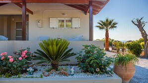 Ein Haus mit Ziegeldach, einer Veranda und einem Garten mit Pflanzen und einem großen Blumenkasten.