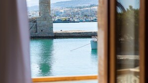 Udsigt fra en balkon over en havn med et fyrtårn, både og en by i det fjerne.