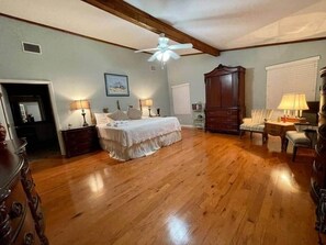 A bedroom with a bed, nightstands, a dresser, a chair, a desk, and a ceiling fan.