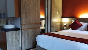Una habitación de hotel con una cama, una mesita de noche con lámpara, un espejo y un ventanal grande.