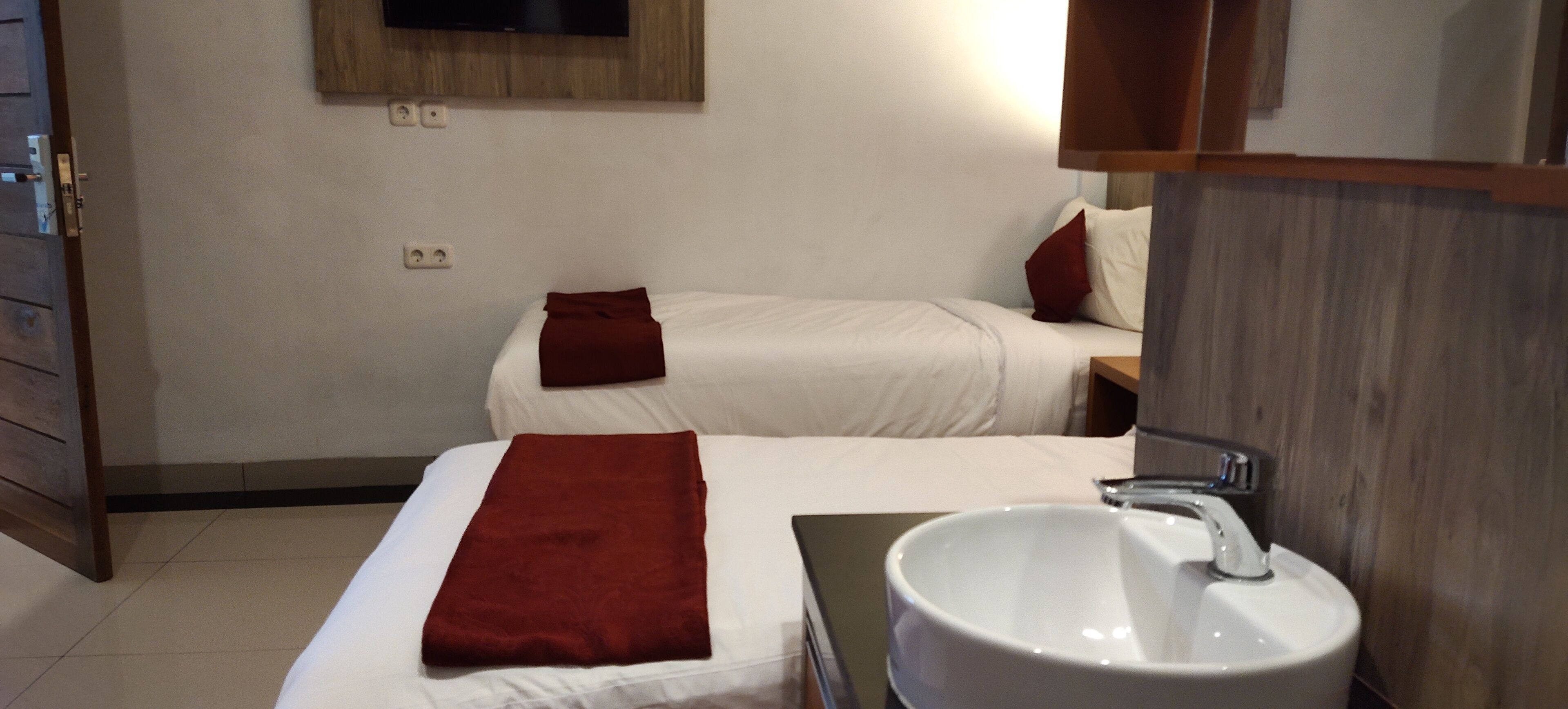 A hotel room with two beds, a white sink, and a wooden cabinet.