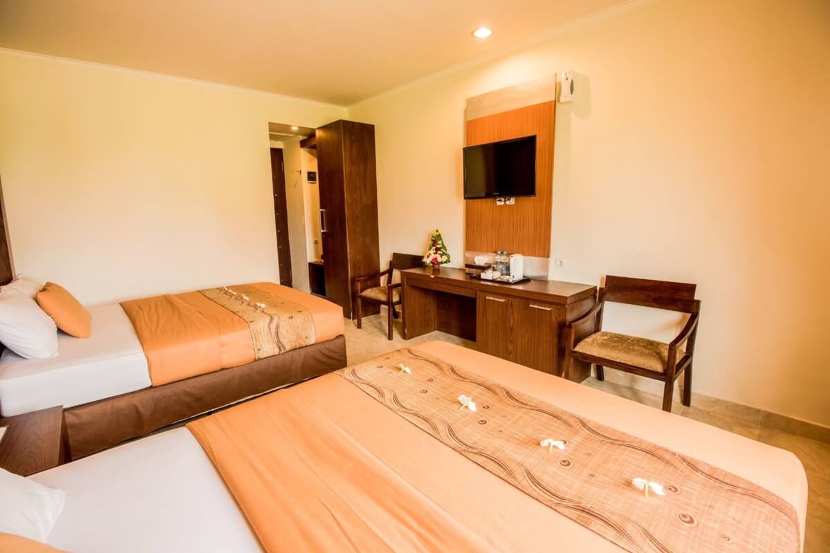 A hotel room with two beds, a desk, a chair, and a TV mounted on the wall.