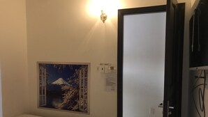 A bedroom with a bed, a wall-mounted picture of Mount Fuji, a light fixture, and a door to another room. - Dung Khanh Motel (Ho Chi Minh City)
