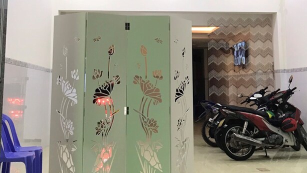 A room with a green cabinet with floral designs, a blue chair, and a motorcycle parked in the corner. - Dung Khanh Motel (Ho Chi Minh City)