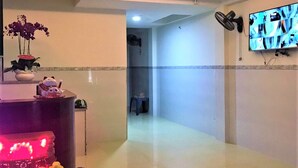 A hotel lobby with a reception desk, a TV mounted on the wall, a fan, and a tiled floor. - Dung Khanh Motel (Ho Chi Minh City)