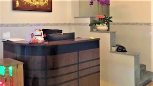 A reception desk with a decorative cat figurine, a framed artwork above, and a potted plant on the wall. - Dung Khanh Motel (Ho Chi Minh City)