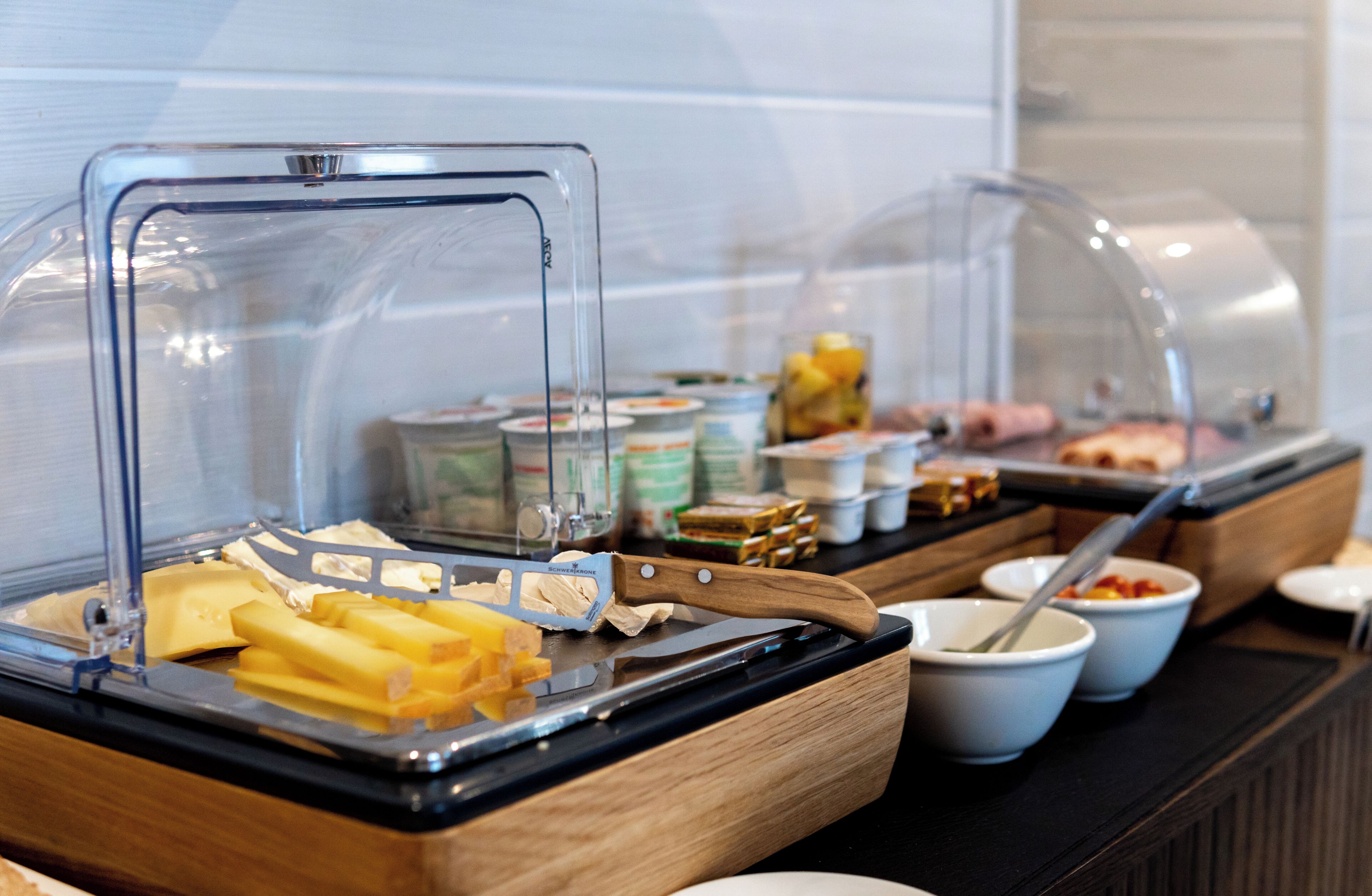 A buffet with various food items including cheese, fruits, and condiments.