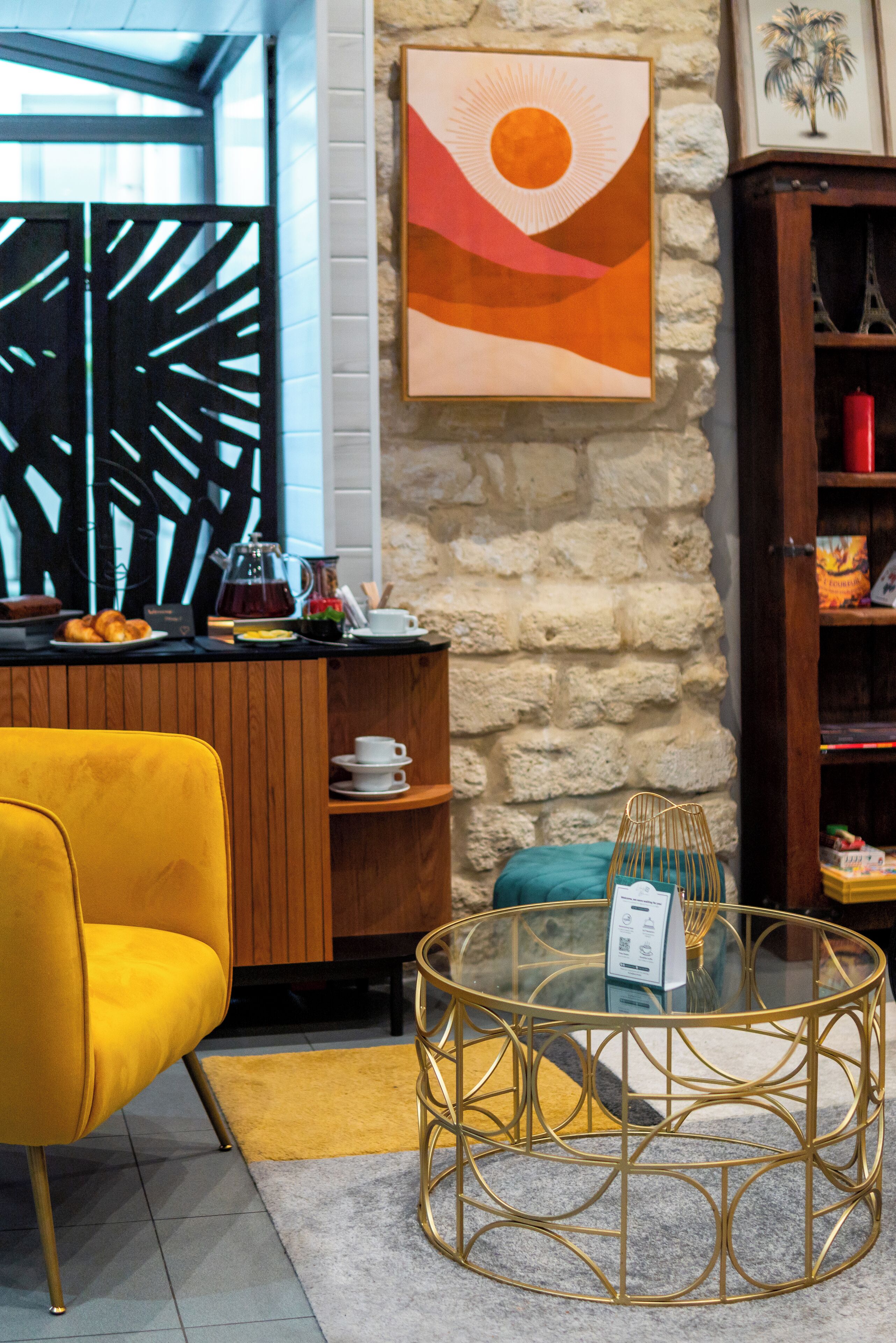 A modern interior with a yellow armchair, a glass coffee table, a stone wall, and a wooden cabinet.