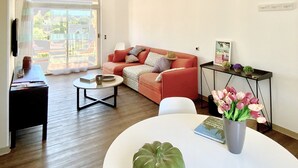A living room with a sofa, coffee table, and a side table with a vase of flowers. - Renovated Bastide, Capelan peninsula, quiet (Bandol)