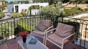 A balcony with two chairs and a table, a yellow awning, and a view of a residential area with trees and buildings. - Renovated Bastide, Capelan peninsula, quiet (Bandol)