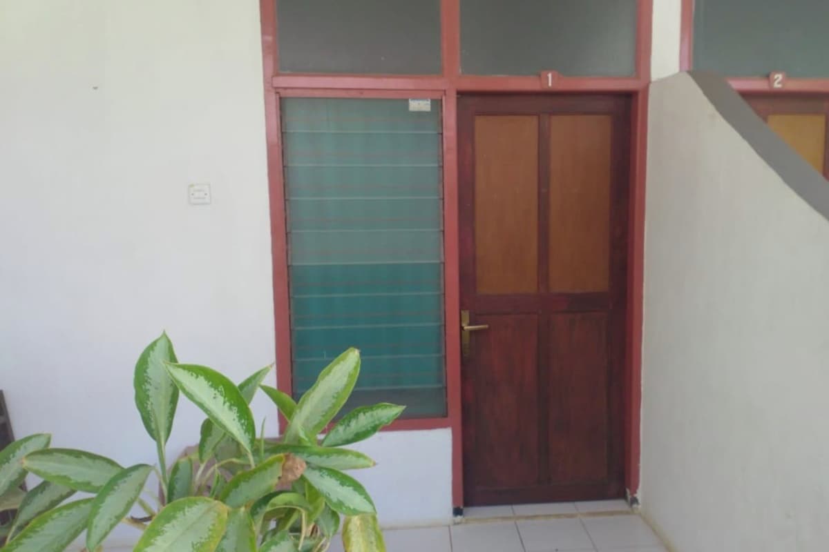 A building with a wooden door, a green window, and a white wall.