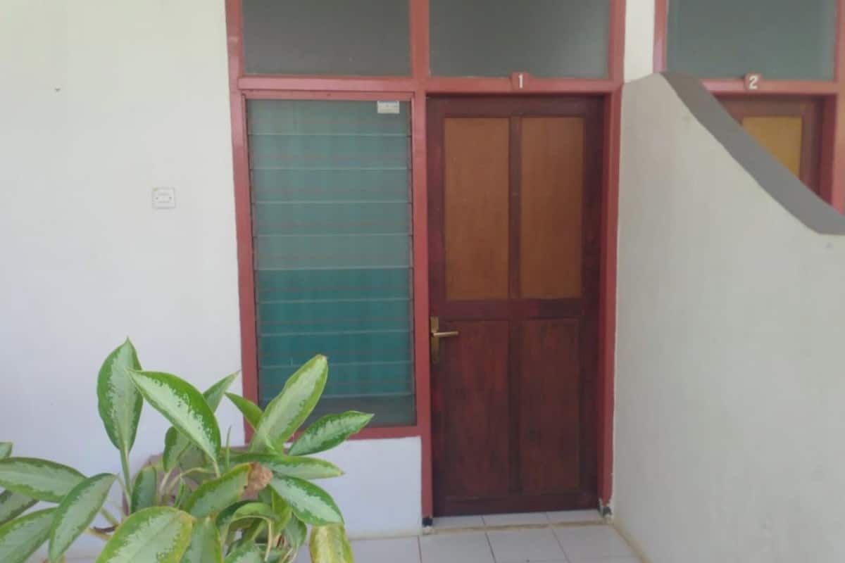 A building with a wooden door, a green window, and a white wall.