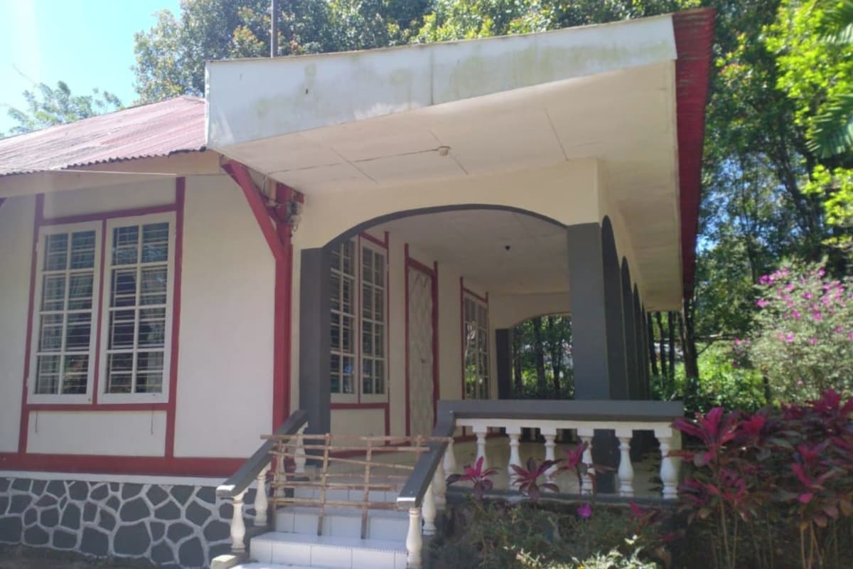 Un bâtiment avec des fondations en pierre, une façade rouge et blanche et une entrée couverte avec un escalier.