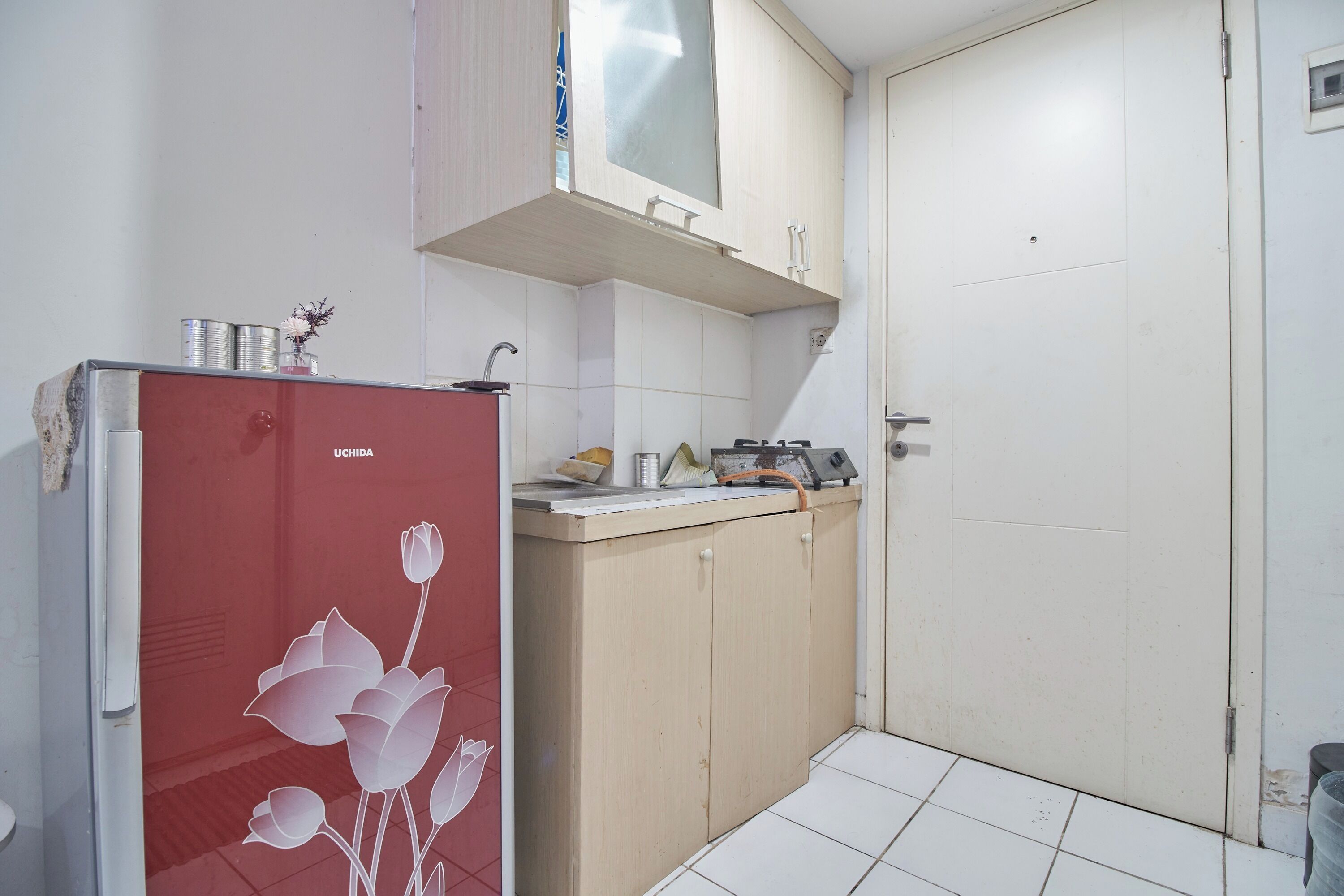 A compact kitchen with a refrigerator, a sink, and cabinets.
