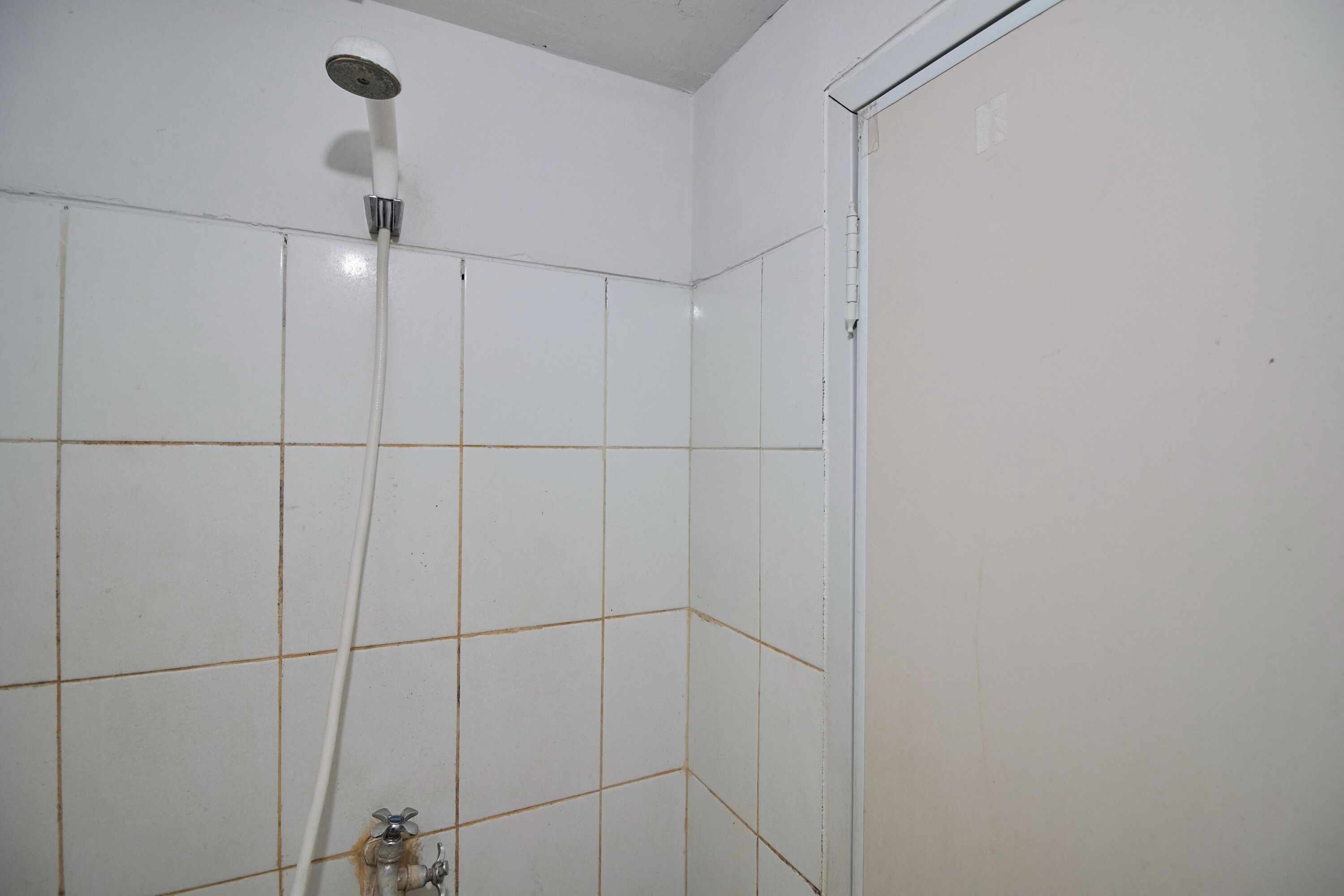 A bathroom with white tiled walls and a shower.